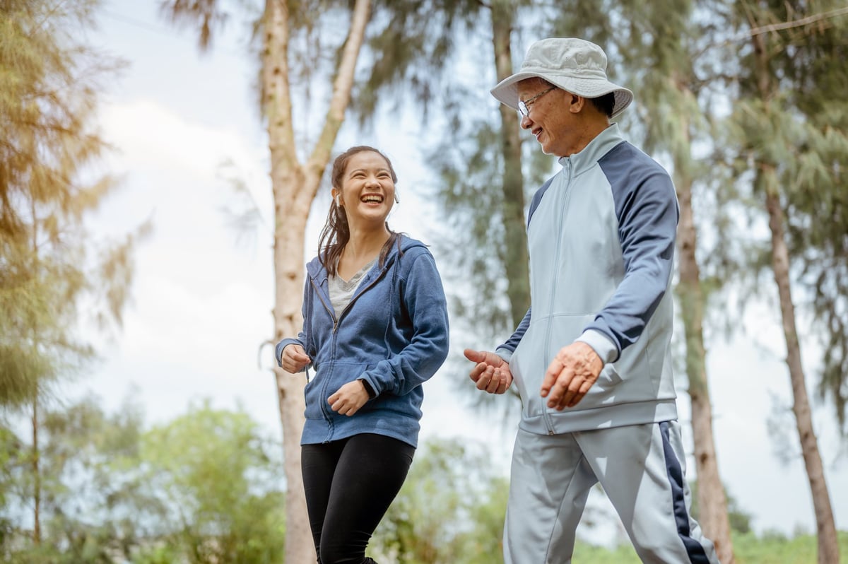 A woman and grandfather are walking jogging on the street at the park. Grandfather talk about the story of past life experiences. Healthy and lifestyle concept.